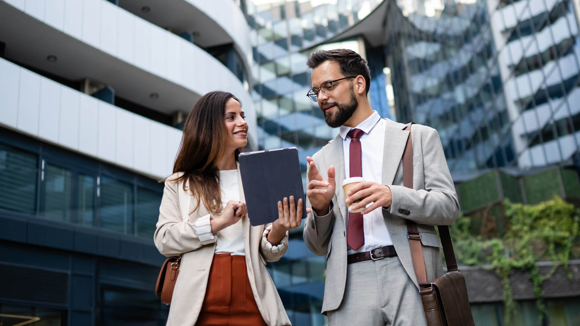 Male and female professionals reviewing the January 2025 jobs report on an iPad looking at December 2025 labor market and ecconomy trends.