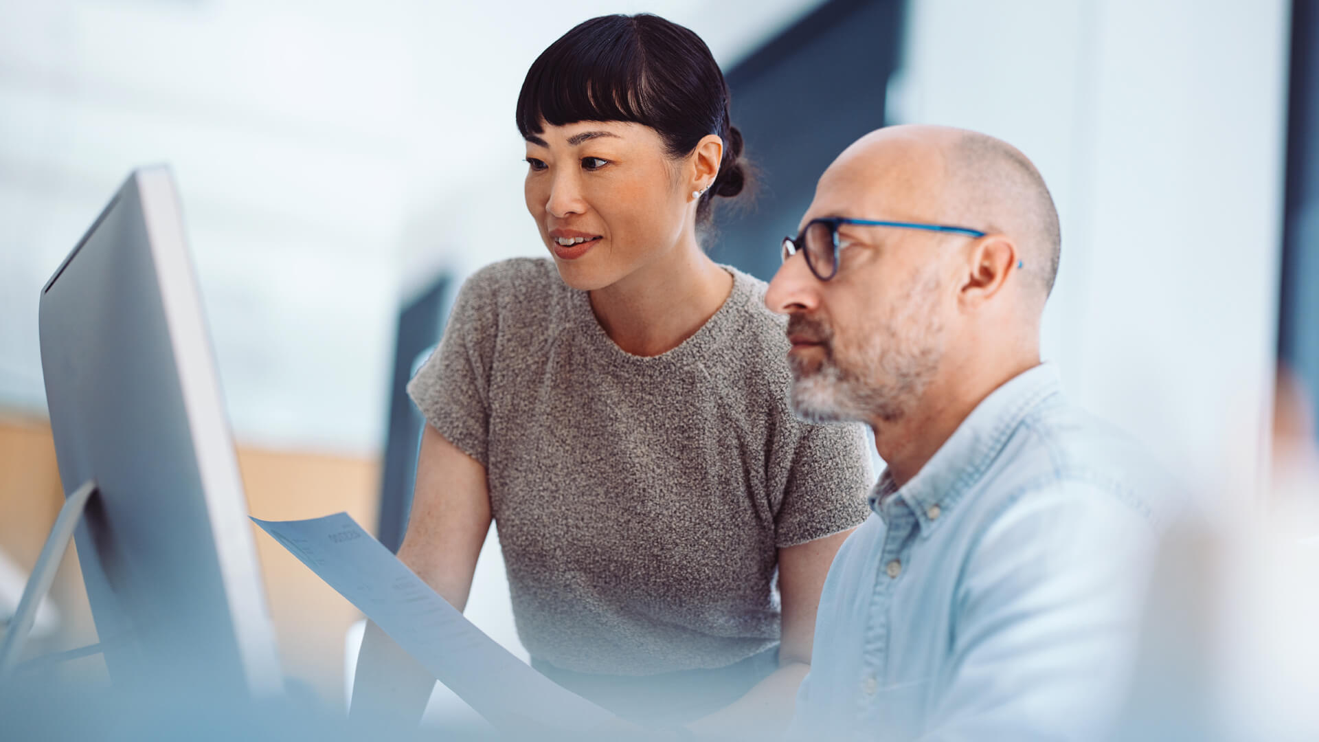 Male and female professionals reviewing the July 2026 jobs report looking at June labor market and economy trends.