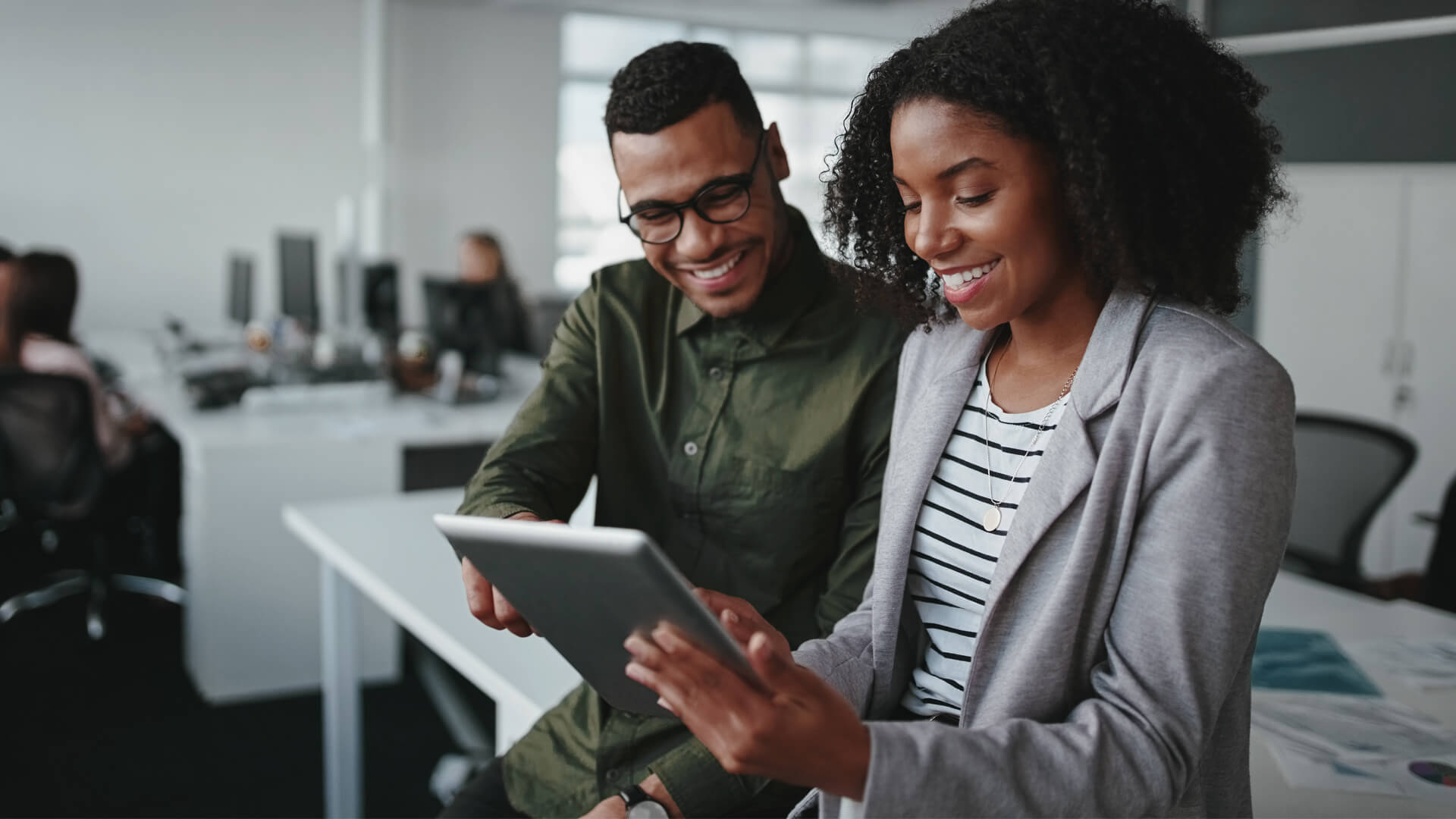 Male and female professionals review the October 2026 jobs report on a tablet looking at September 2026 labor market and economy trends.