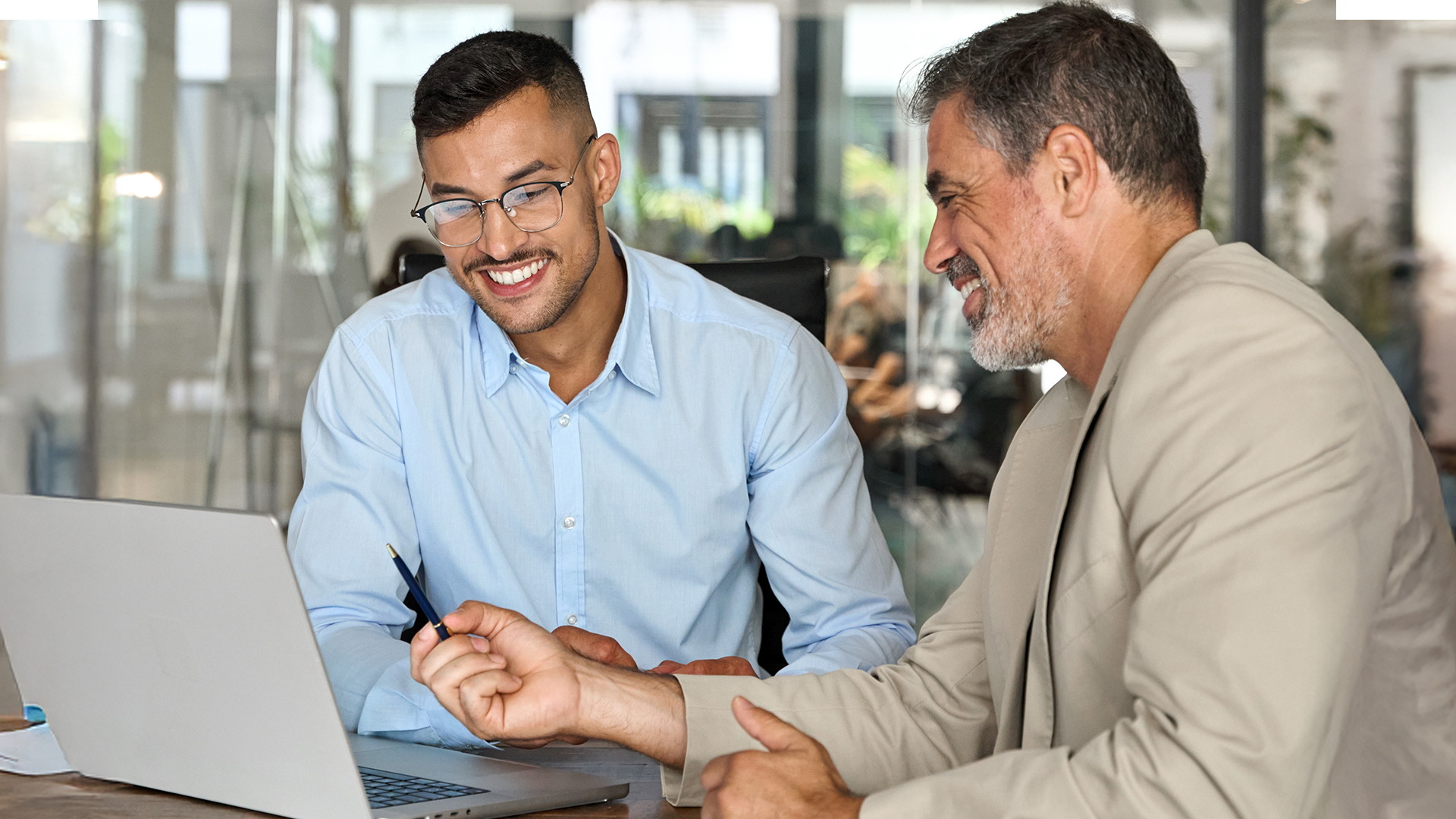 Male coworkers reviewing the September 2025 jobs reporting on a laptop looking at August 2025 labor market and economy trends.