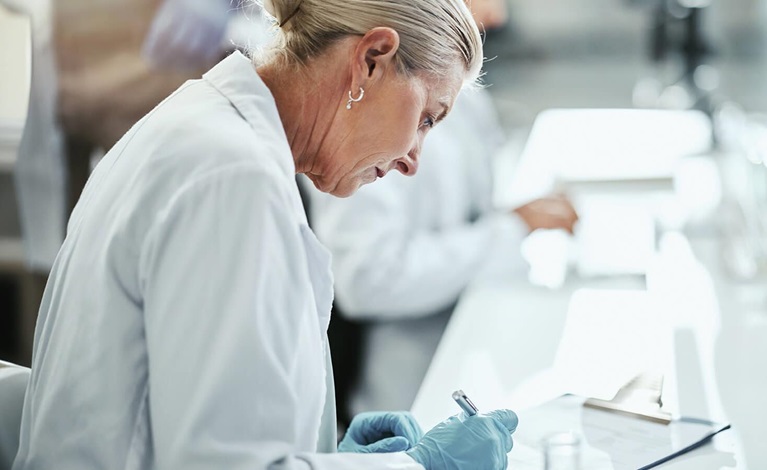Female lab technician reviewing instructions and documents for samples.