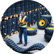 A worker in orange vest writing on clipboard in warehouse